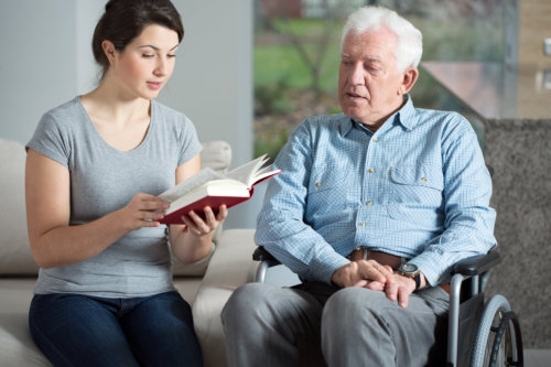 caregiver reading book for elderly man